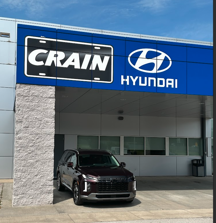 A maroon Hyundai SUV parked beneath the Crain Hyundai Fayetteville dealership awning.